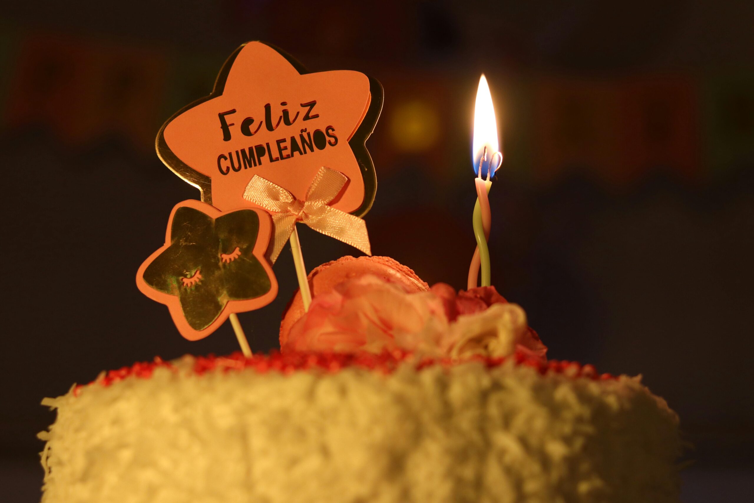 A vibrant birthday cake featuring a lit candle and festive decorations in a dimly lit setting.
